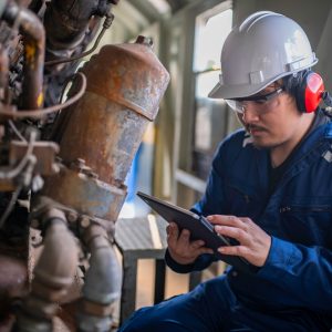 mechanic looking at IPad tablet in front of rusty equipment